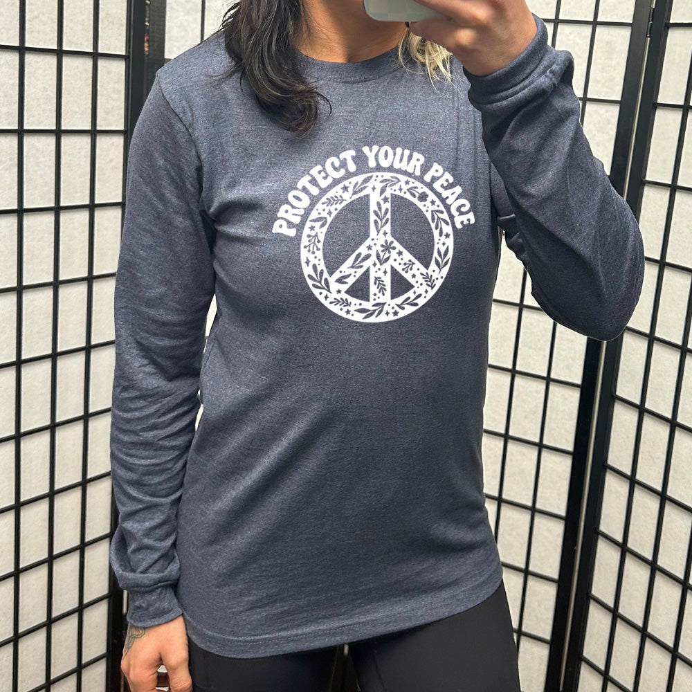 Heather navy long sleeve with the text "protect your peace" and a peace sign graphic on it
