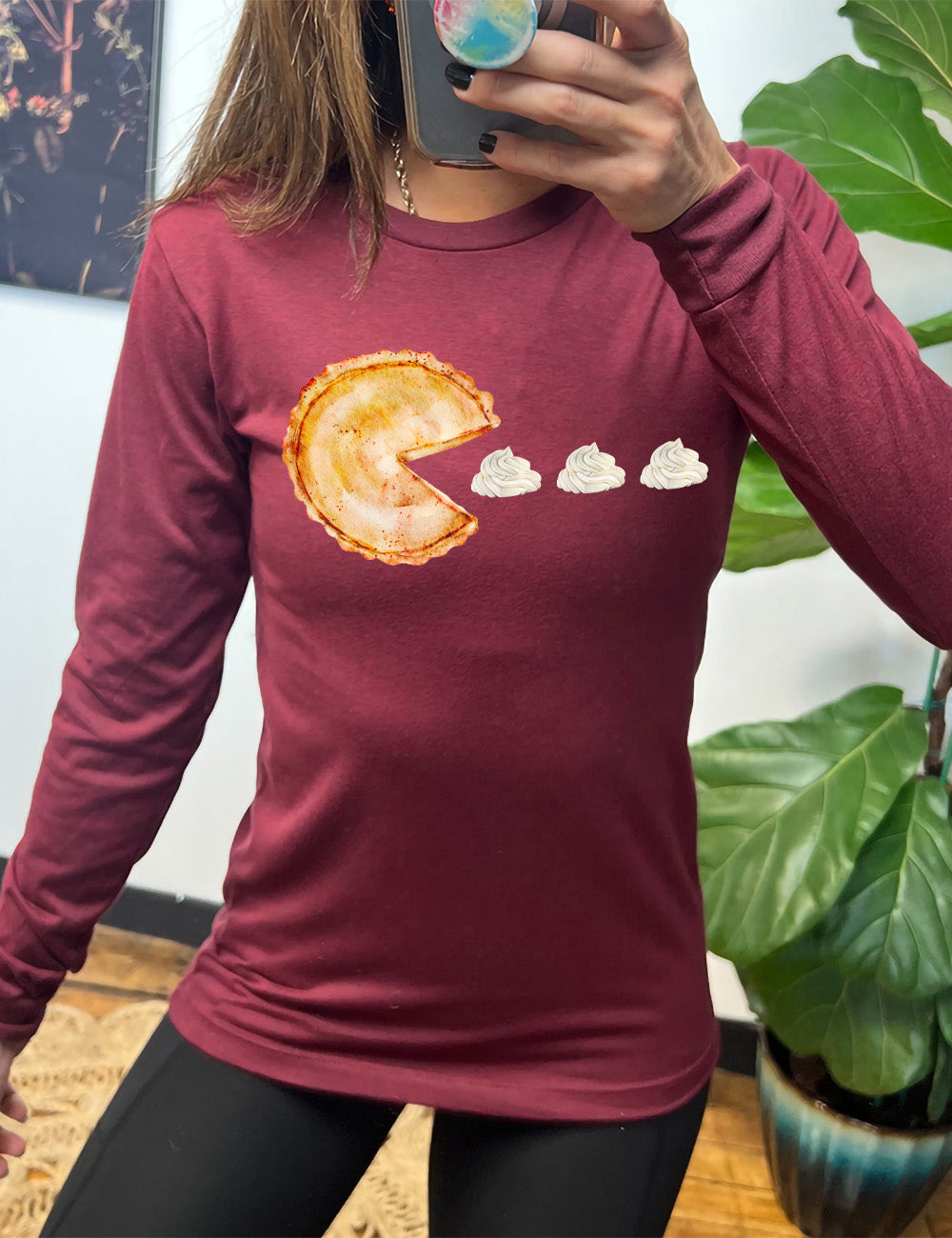 heather cardinal long sleeve tee with the graphic of a pumpkin pie, with the a slice taken out of it so that it looks like Pacman, heading in the direction of three dollops of whipped cream