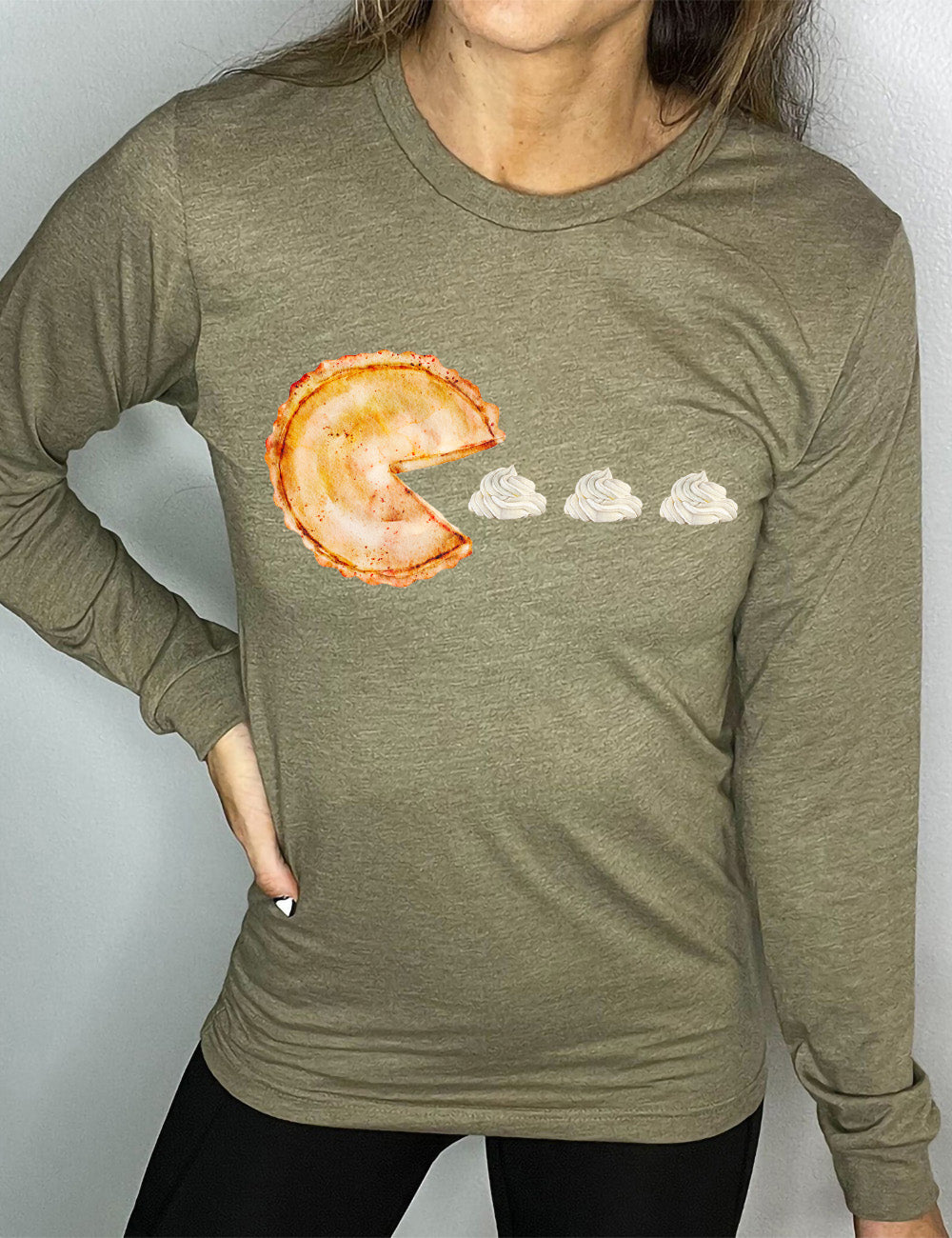 heather olive long sleeve tee with the graphic of a pumpkin pie, with the a slice taken out of it so that it looks like Pacman, heading in the direction of three dollops of whipped cream