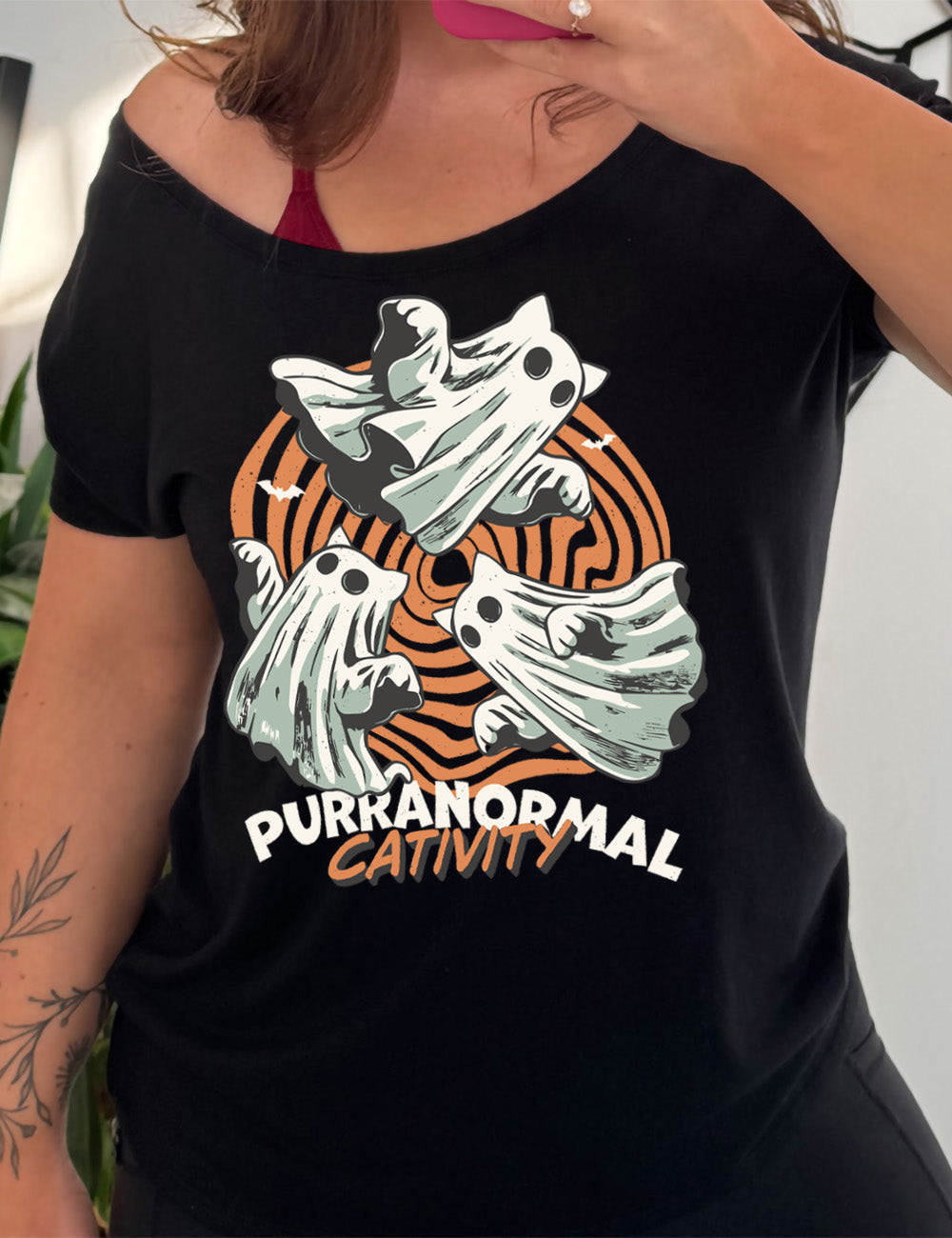 black slouchy tee with the graphic of three cat-ghosts swirling in a circle, in front of a spiraled background, with words underneath saying "purranormal cativity"