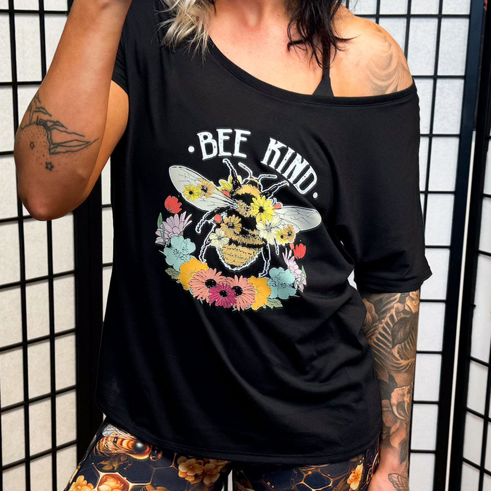 model wearing a black slouchy shirt that says "bee kind" with a bee and flower graphic on it