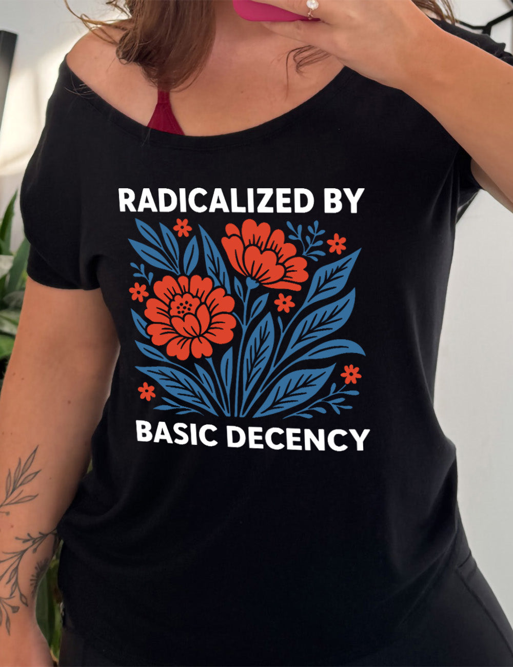 black slouchy tee with the graphic of a blue and red flower bed with the words "radicalized by" (above) and "basic decency" (below)