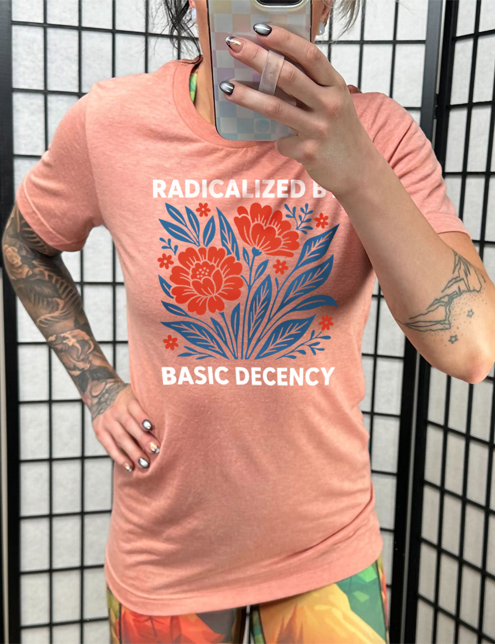 sunset unisex tee with the graphic of a blue and red flower bed with the words "radicalized by" (above) and "basic decency" (below)