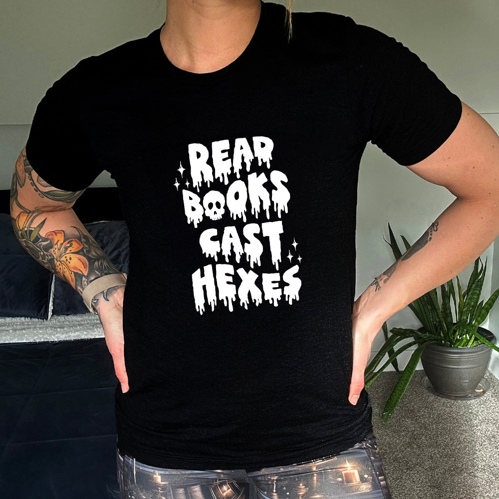 black shirt with the text "Read Books Cast Hexes" on it