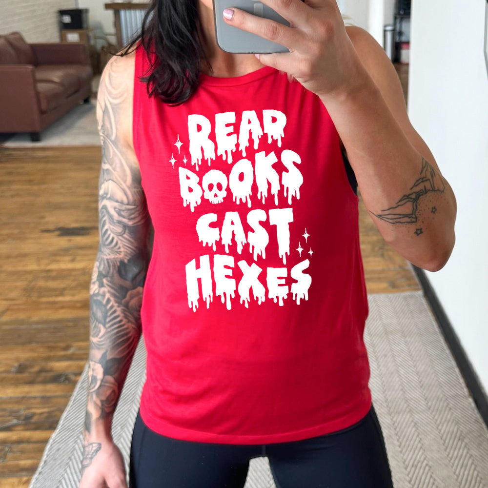 red muscle tank with the horror-style text saying "Read Books Cast Hexes" on it, with one of the "o"s being a skull, with a few little stars
