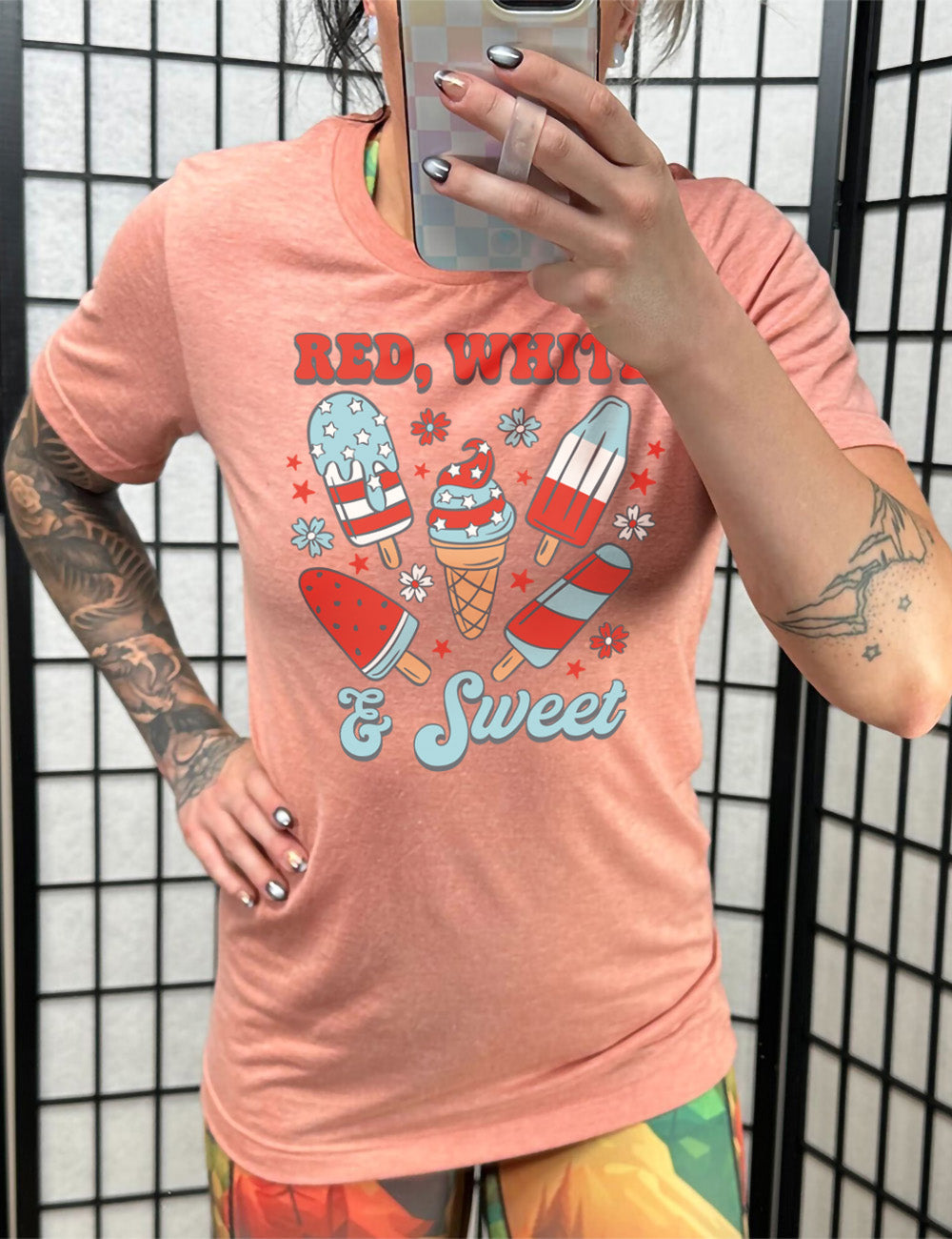 sunset unisex tee with the words "red, white, & sweet" on it, around the graphics of American flag-designed popsicles and an ice cream comb (5 total treats), and some flowers and stars 