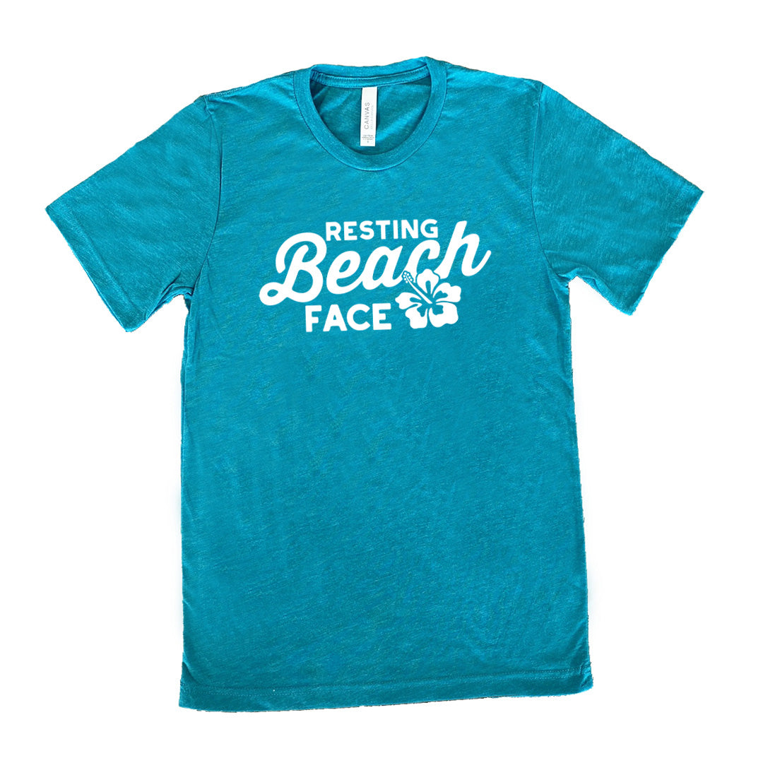 Teal colored shirt with a flower graphic on it that says "Resting Beach Face" 