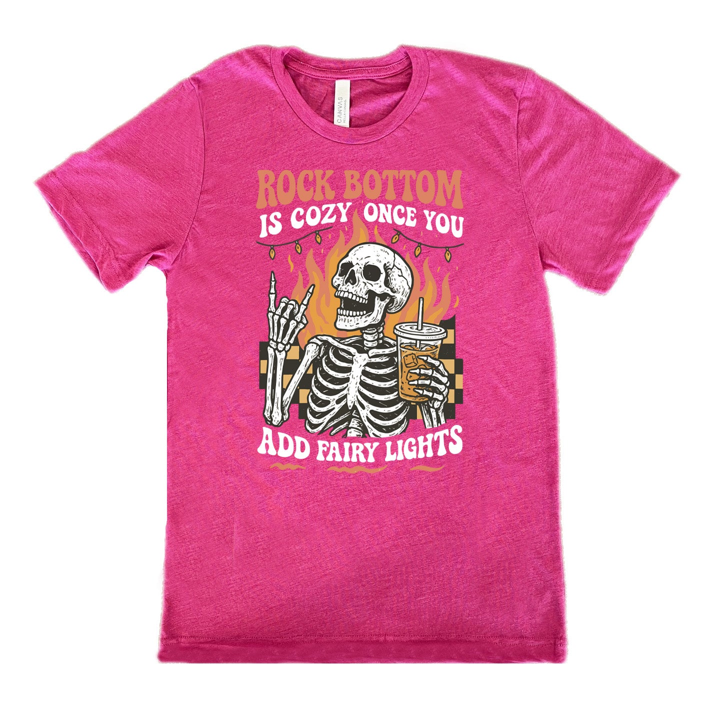 berry unisex tee with the words "rock bottom is cozy once you add fairy lights" with the graphic of a skeleton giving the rocker sign with one hand while holding an iced drink in the other, with a background of some checkerboard, some flames, and a string of fairy lights above the flames