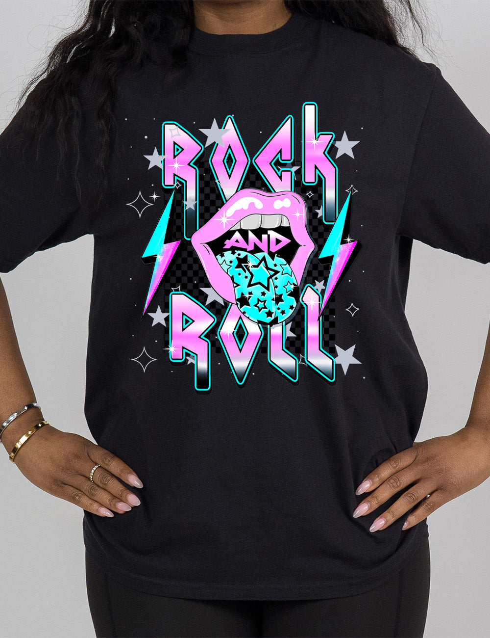 black modern tee with print placement on the front, with the words "rock and roll" on it, with the word "and" within the large graphic of a mouth, with it's tongue sticking out with stars on it, and a number of stars around the words, with a lightning bolt on both sides of the mouth 