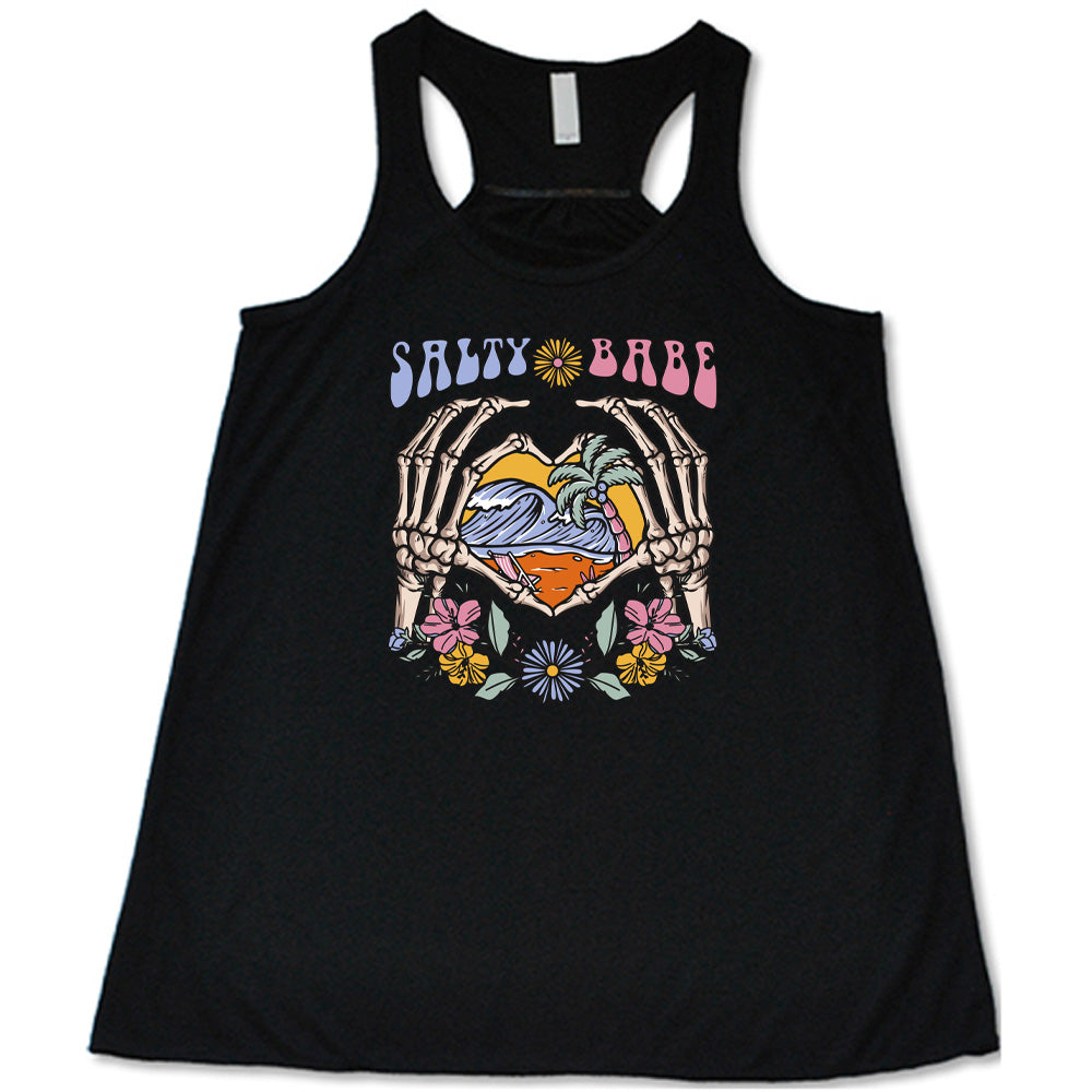 Black colored flowy tank with a skeleton heart hands around ocean waves graphic on it that says "Salty Babe" 