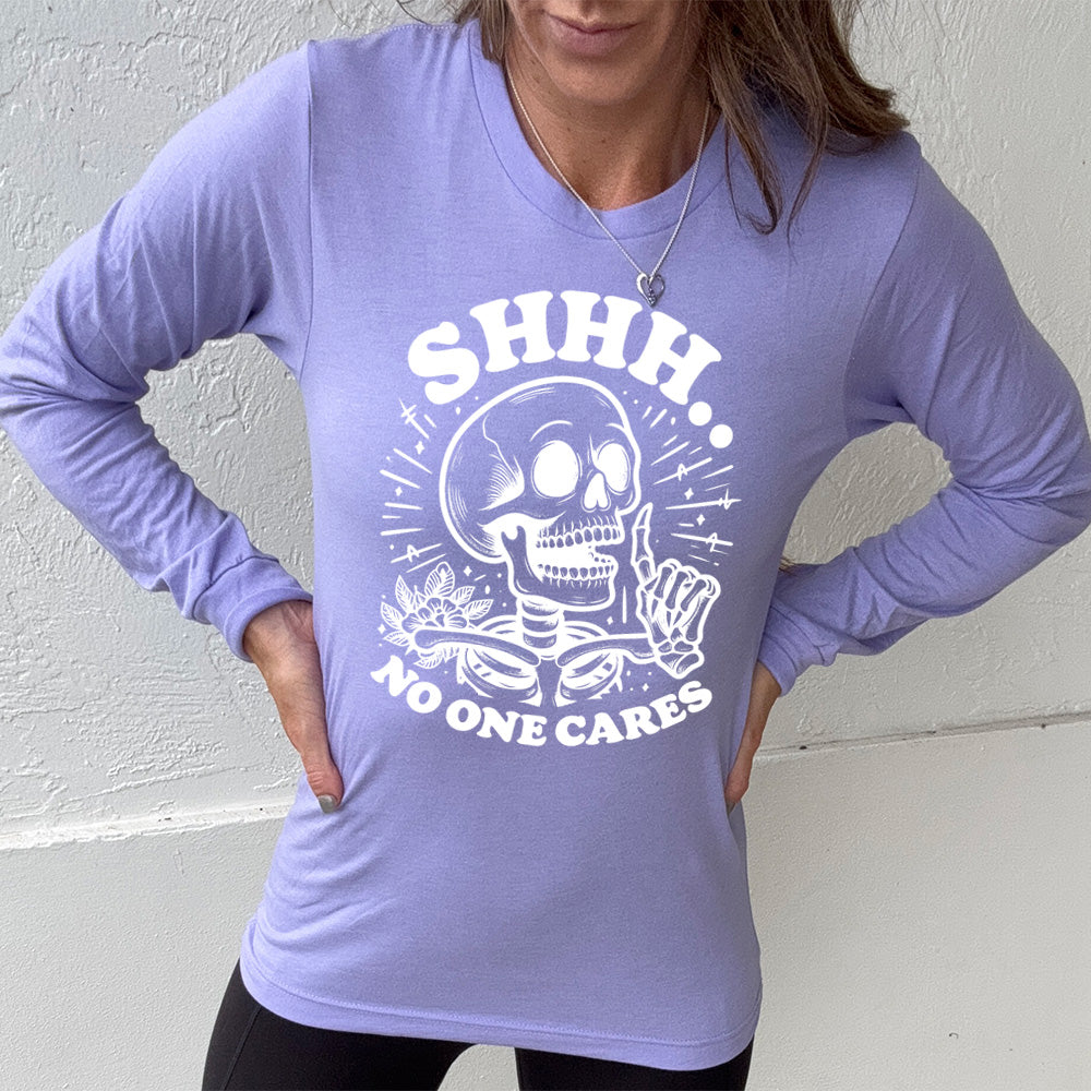 heather dark lavender long sleeve with the words "Shhh.. no one cares" on it, with the graphic of a skeleton holding a finger to its lips 