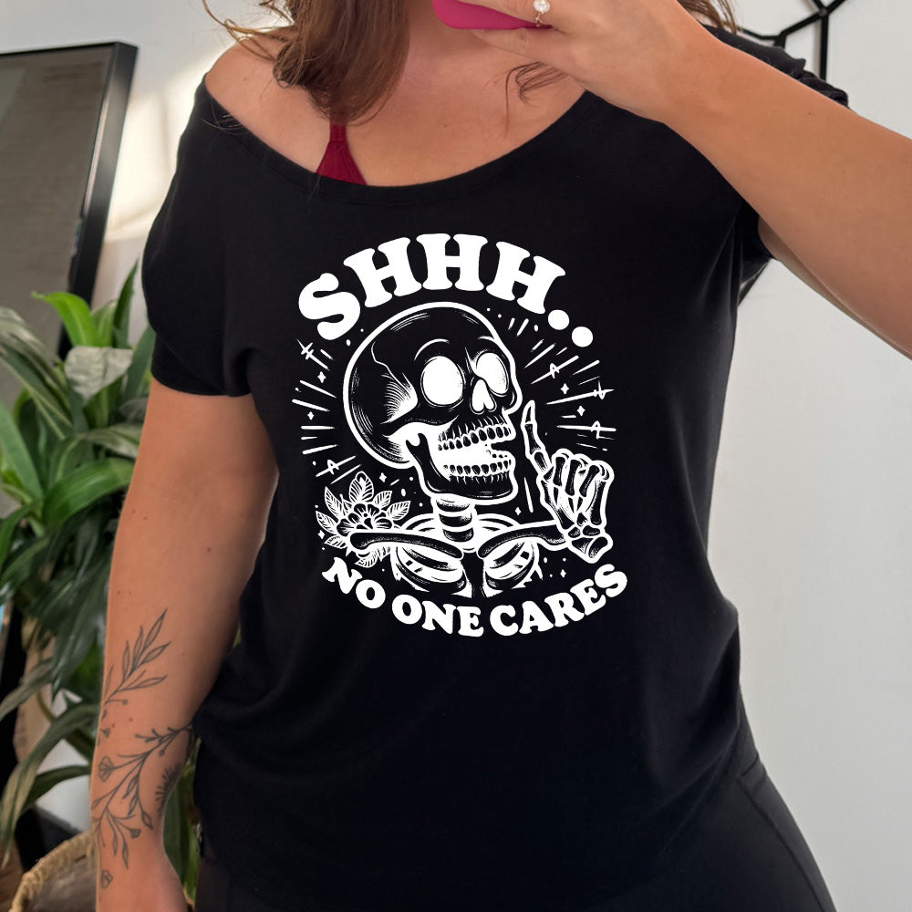 black slouchy tee with the words "Shhh.. no one cares" on it, with the graphic of a skeleton holding a finger to its lips 