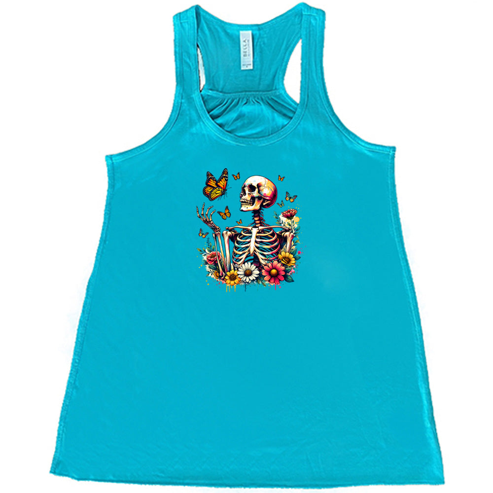 Teal colored flowy tank with a skeleton, butterflies, and flowers graphic on it