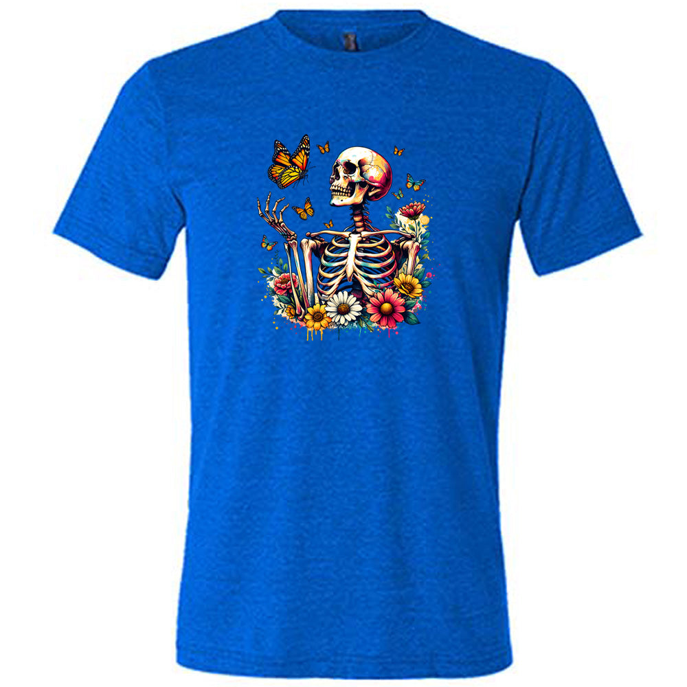 Blue colored shirt with a skeleton, butterflies, and flowers graphic on it