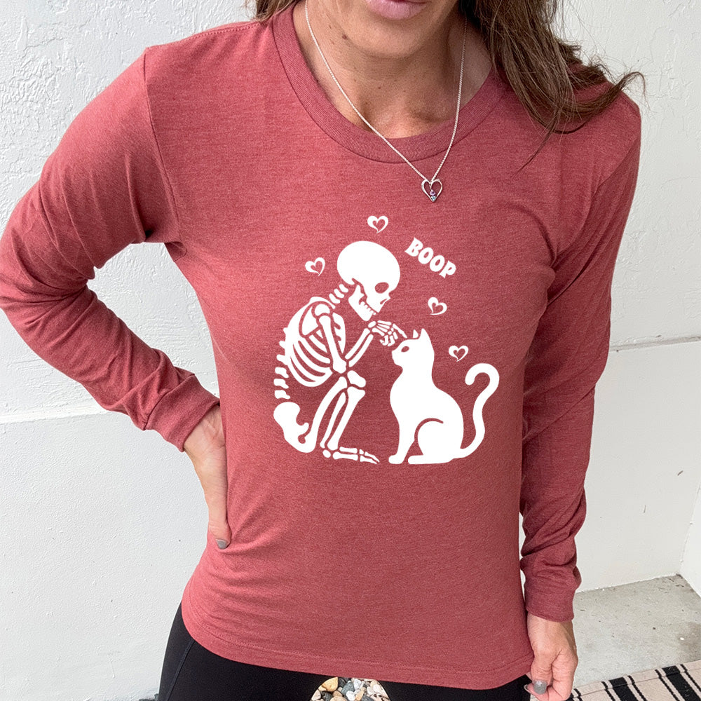 heather clay long sleeve shirt with the graphic of a sitting skeleton touching the head of a sitting cat, with the word "boop" above this action, and four little hearts around them