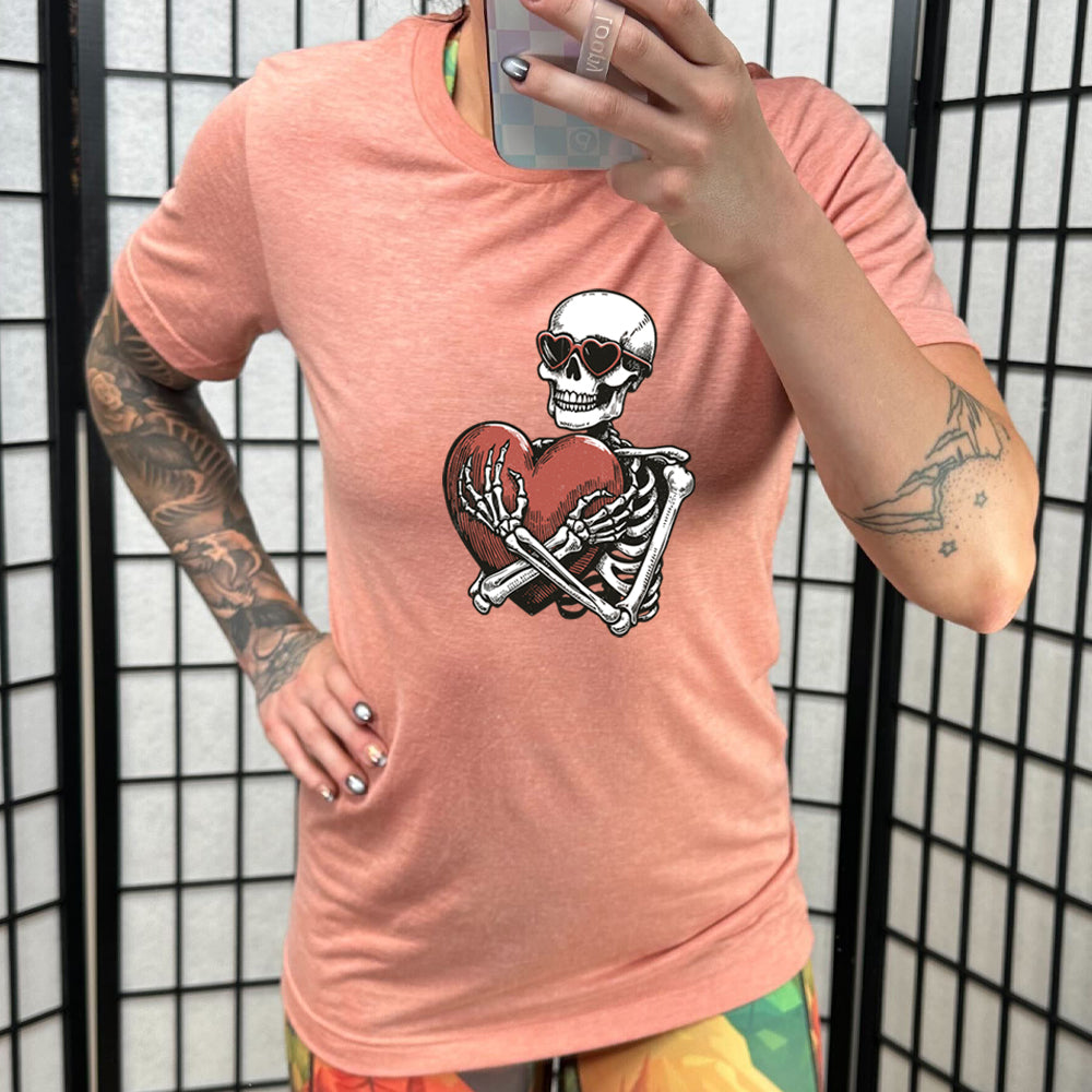 coral shirt with a skeleton hugging a heart graphic on it