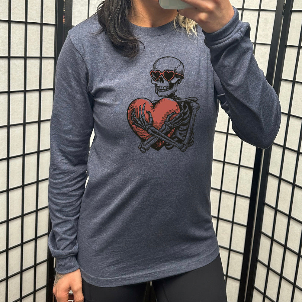 heather navy long sleeve shirt with the graphic of a skeleton, wearing sunglasses, hugging a big heart close