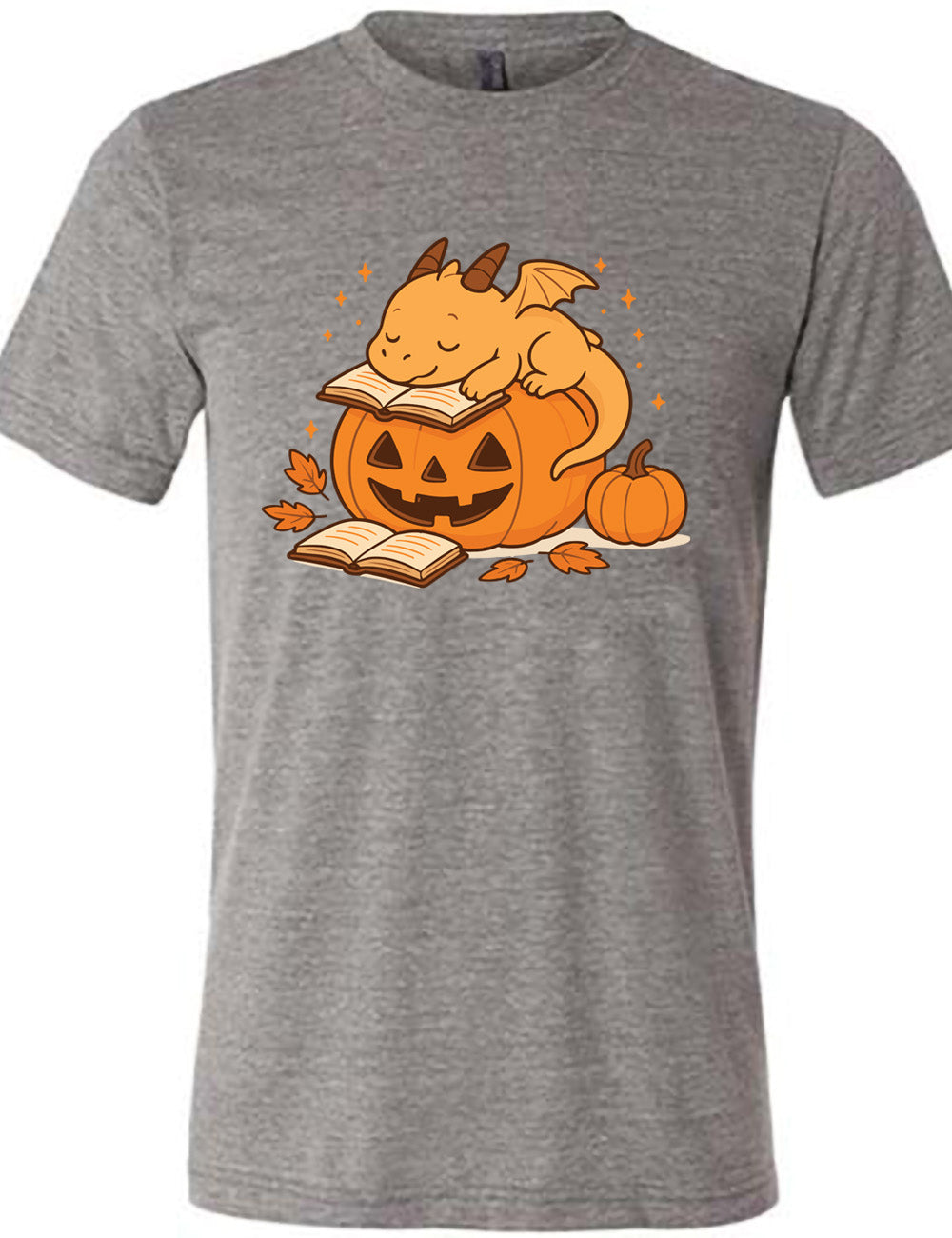 grey unisex tee with the graphic of a cartoon-style dragon sleeping, with its head in its open book, on top of a jack-o-lantern, with another open book and small pumpkin next to all this, and a scattering of stars, and a few leaves