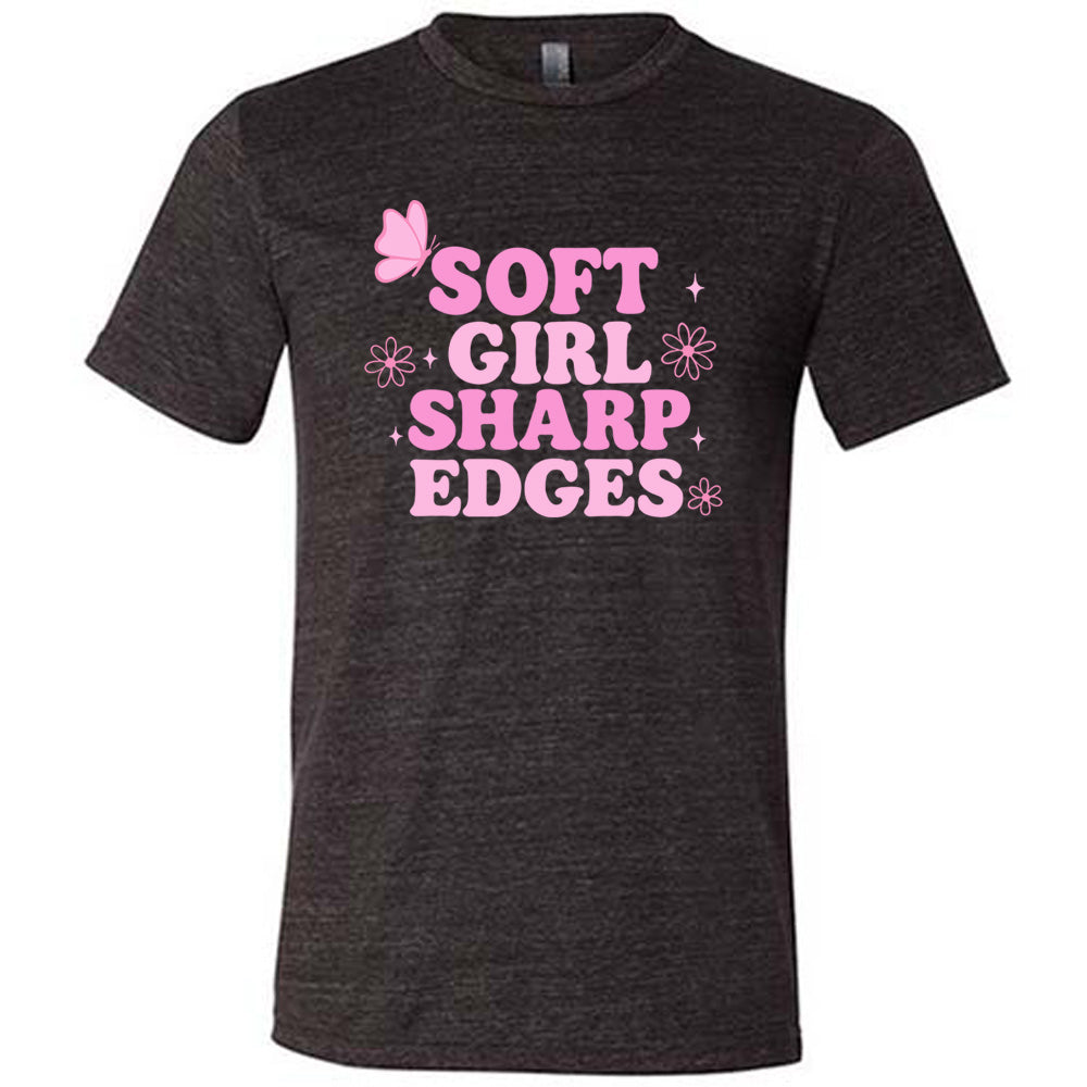 black unisex tee with the words "soft girl sharp edges" in all caps, with graphics of a few little flowers and stars and one butterfly 