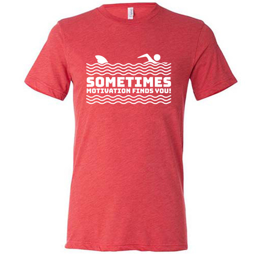 red unisex tee with the words "sometimes motivation finds you!" in between the lined graphic of waves of the sea, and on top of the waves is the graphic of a figure swimming away from a fin in the water behind