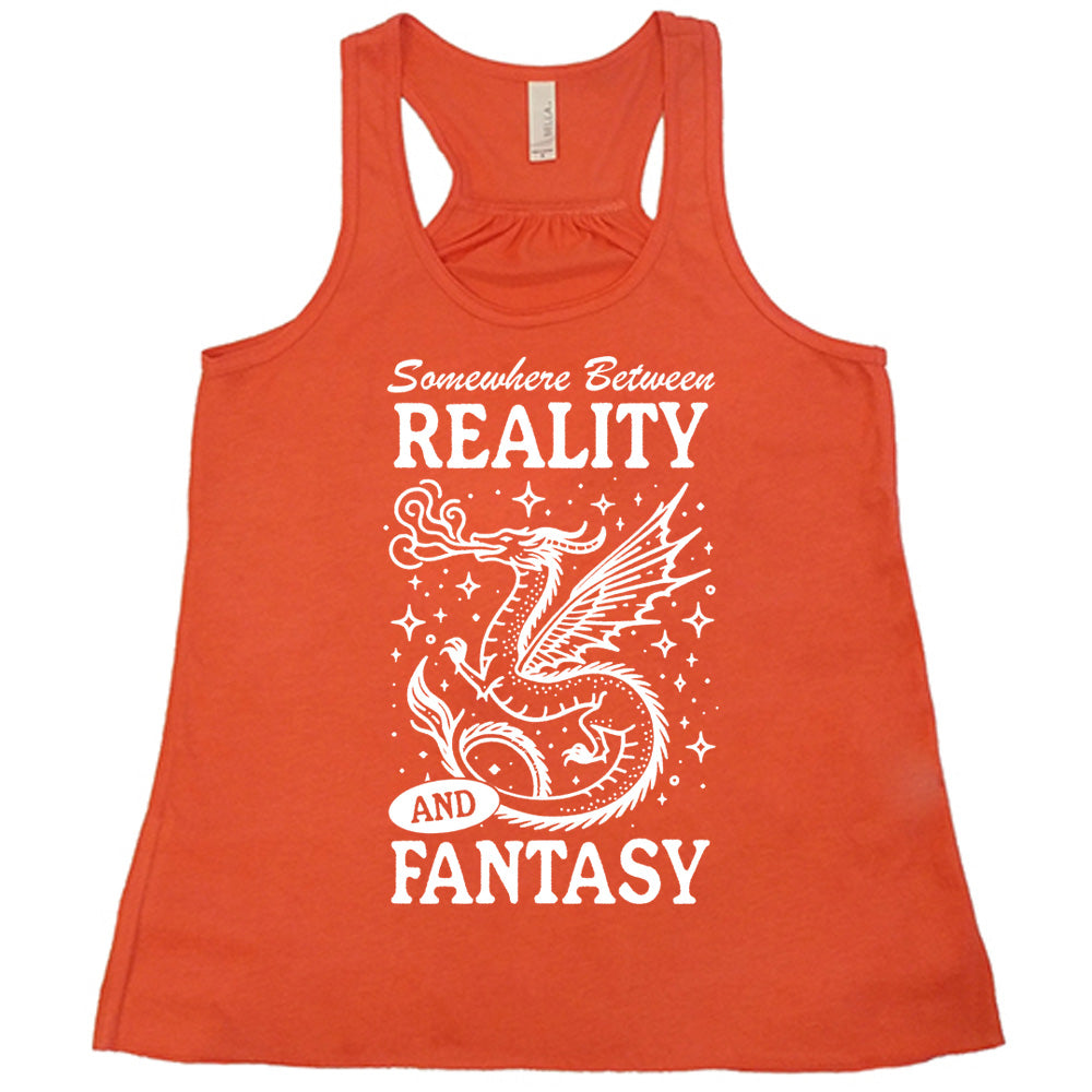 coral racerback flowy tank with the words "somewhere between reality and fantasy" on it, around the graphic of a dragon among stars, breathing fire