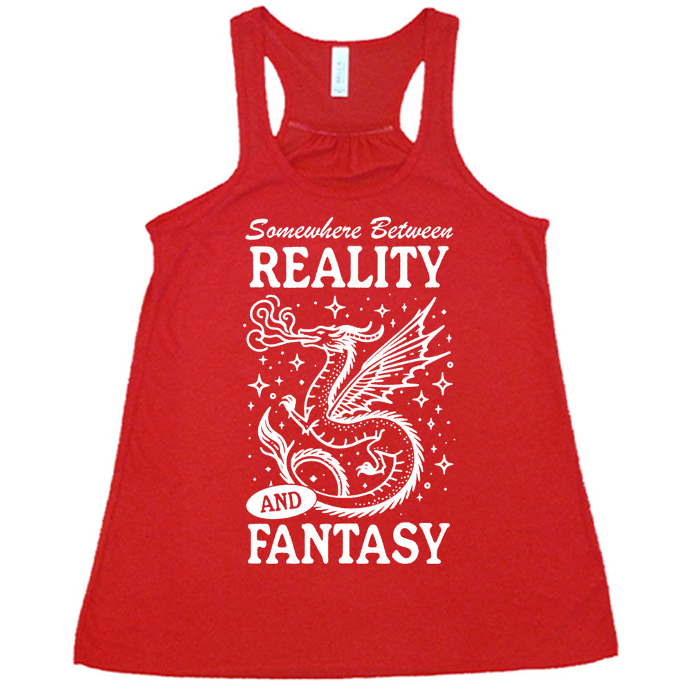red racerback flowy tank with the words "somewhere between reality and fantasy" on it, around the graphic of a dragon among stars, breathing fire