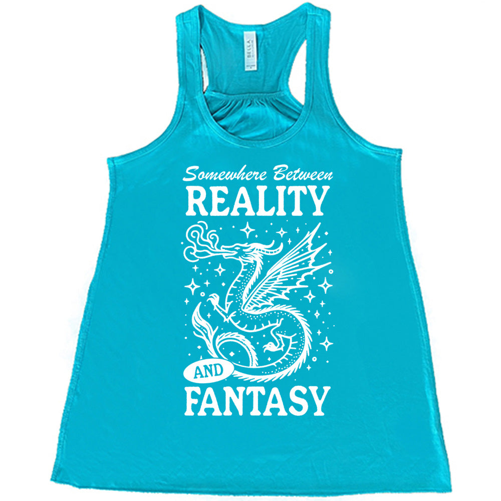 teal racerback flowy tank with the words "somewhere between reality and fantasy" on it, around the graphic of a dragon among stars, breathing fire