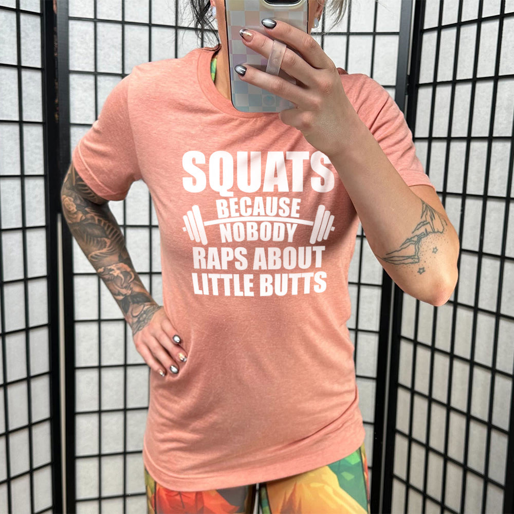 sunset unisex tee with the words "squats because nobody raps about little butts" in all caps with a graphic of a barbell between the words "because" and "nobody"