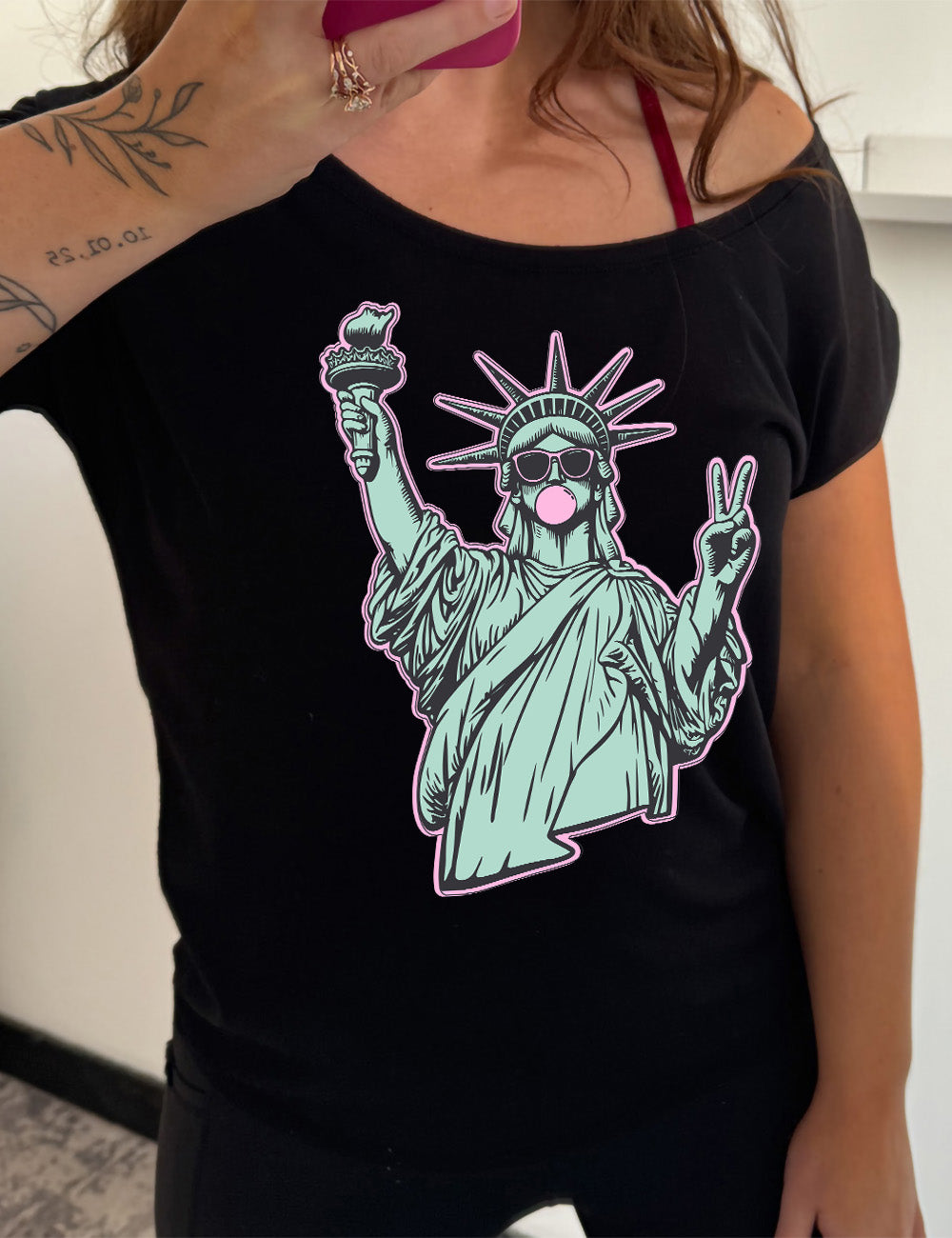 black slouchy tee with the graphic of the statue of liberty, wearing sunglasses, blowing a gum bubble, and giving the peace sign