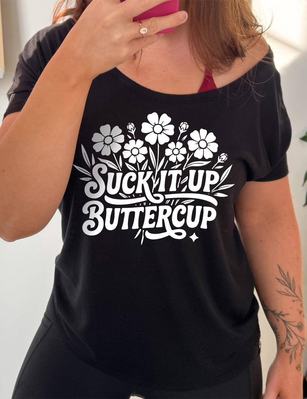 black slouchy tee with the words "suck it up buttercup" on it, with the graphic of a bouquet of flowers, the words in front of the stems