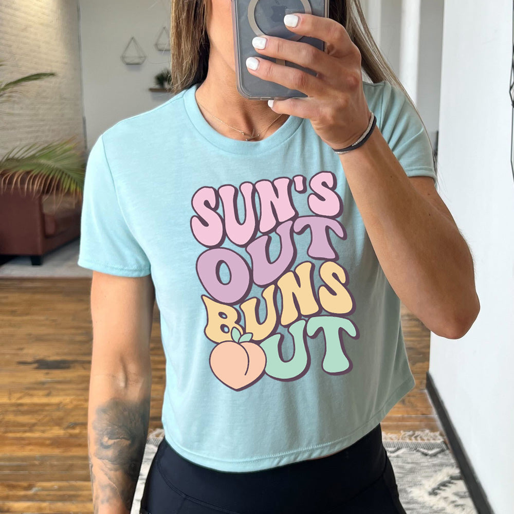 dusty blue  cropped tee with a peach graphic on it that says "Suns Out Buns Out" 