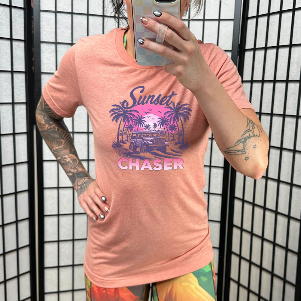 Model wearing sunset colored shirt with a vehicle on the beach graphic on it that says "Sunset Chaser" 