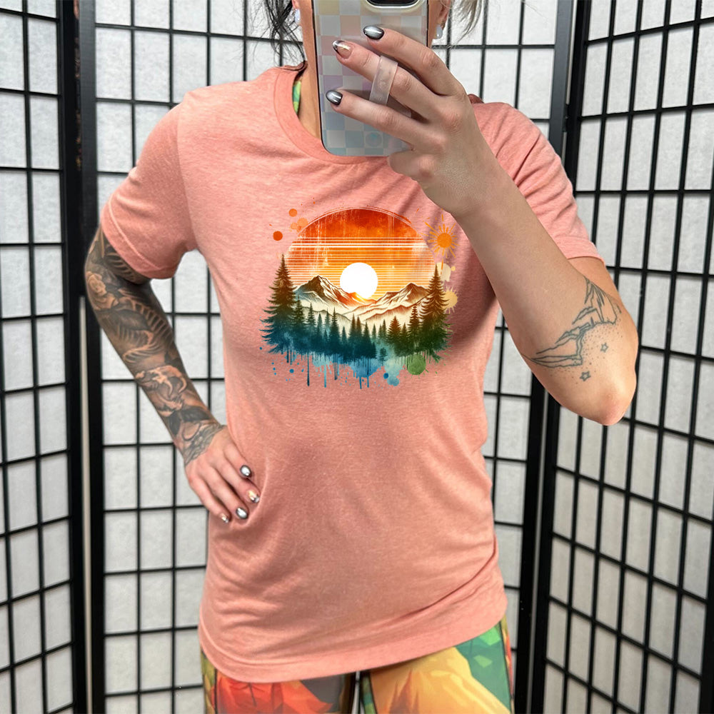 Model wearing sunset colored shirt with a sunset-mountain landscape graphic on it