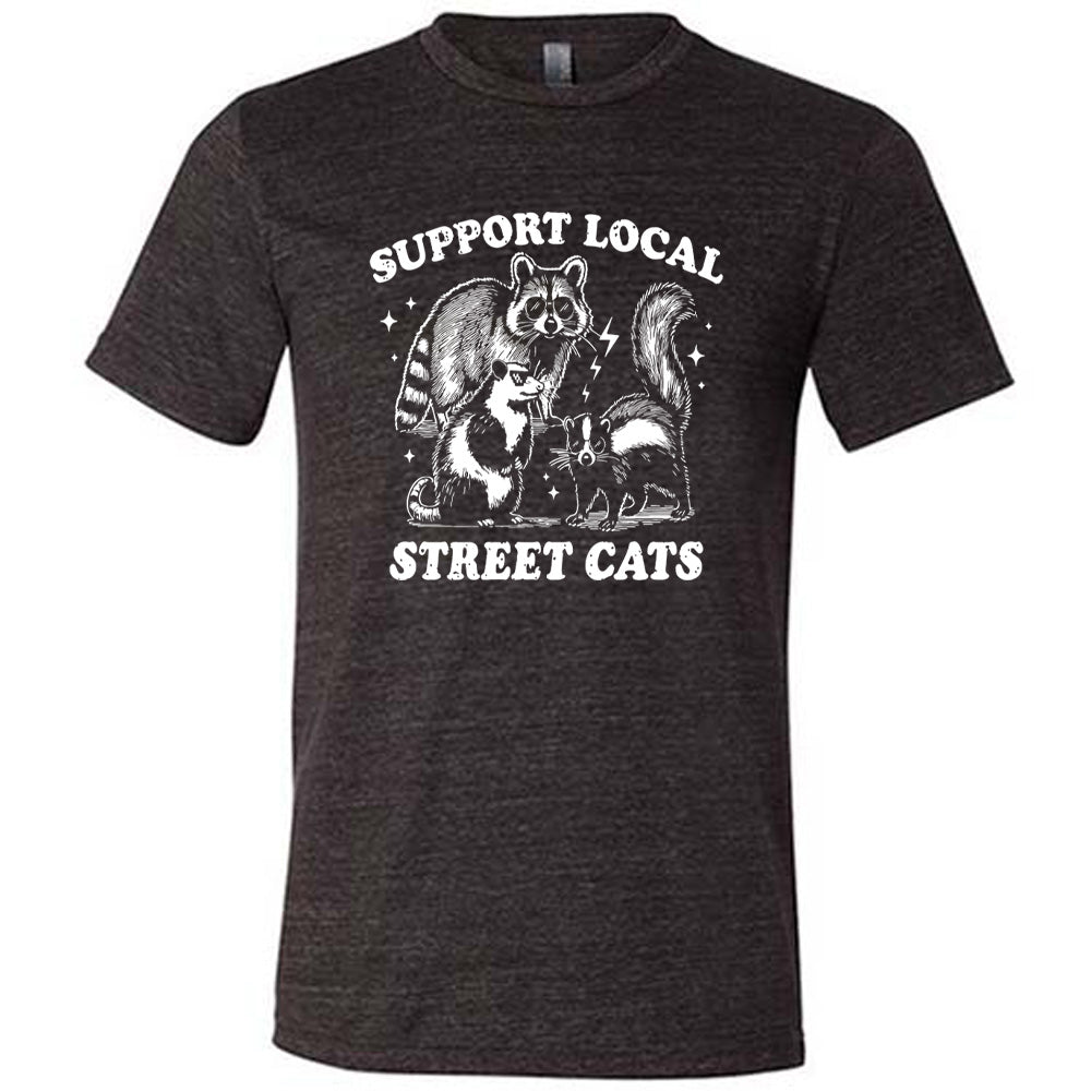 black unisex tee with the words "support local street cats" and the graphics of a racoon, a skunk, and a possum, all wearing sunglasses, with a few little stars and lightening bolts around