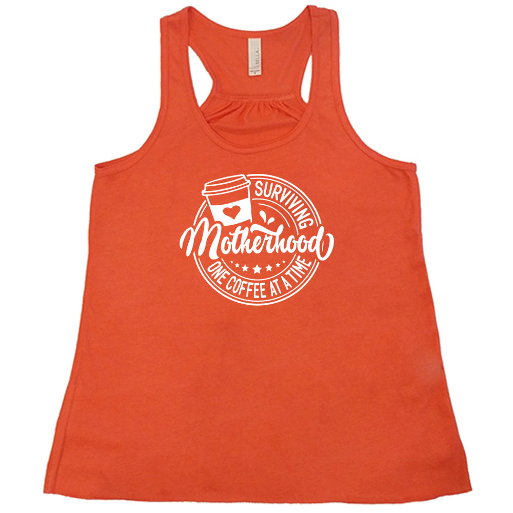 Coral colored flowy tank with a coffee cup graphic on it that says "Surviving Motherhood One Coffee at a Time" 