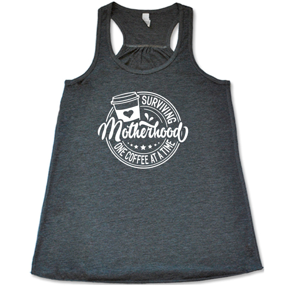 Grey colored flowy tank with a coffee cup graphic on it that says "Surviving Motherhood One Coffee at a Time" 