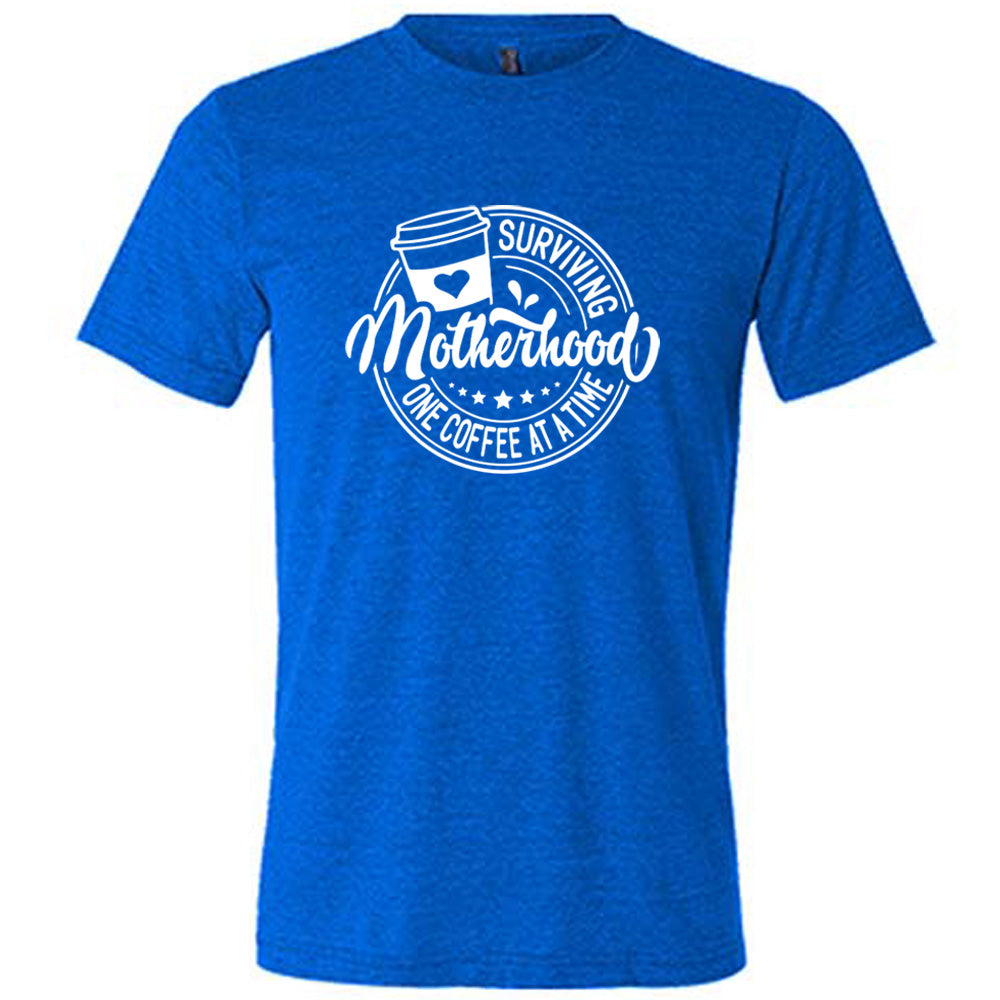 Blue colored shirt with a coffee cup graphic on it that says "Surviving Motherhood One Coffee at a Time" 
