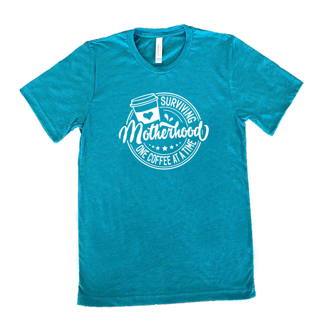 Teal colored shirt with a coffee cup graphic on it that says "Surviving Motherhood One Coffee at a Time" 