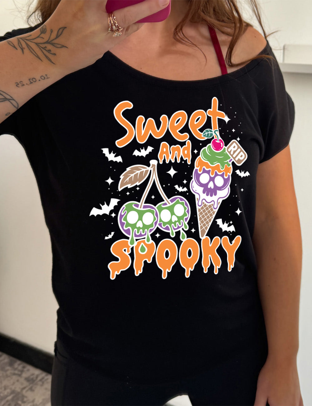 black slouchy tee with the graphic of two cherries on the same branch, with a skull dripping on each of them, and a cherry-topped ice cream cone, with one of the scoops being a skull, with a little "RIP" sign sticking out of the cone, surrounded by bats and stars, and the words starting on top and ending below the graphics saying "sweet and spooky"