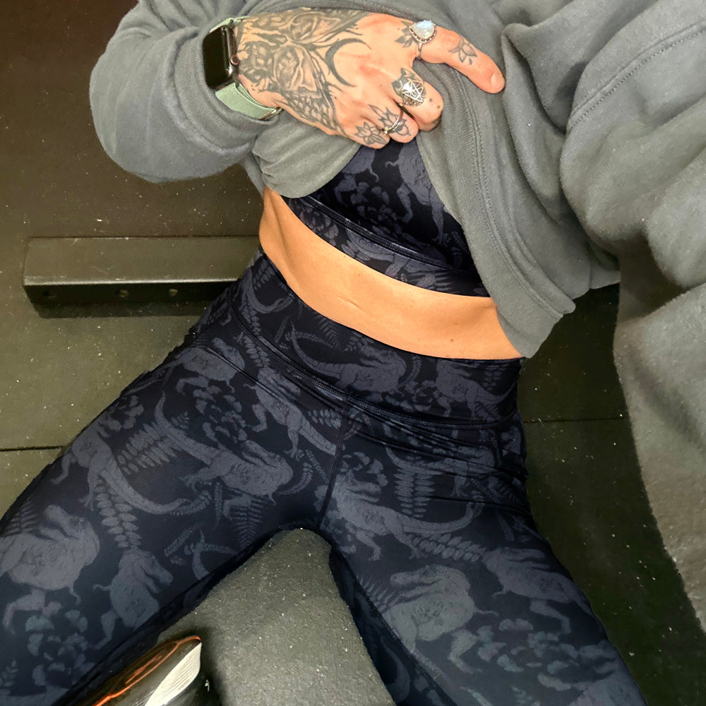 model lifting up shirt showing the dino patterned leggings and bra