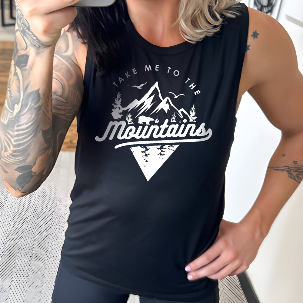 Model wearing black colored muscle tank with a mountains graphic on it that says "Take Me To The Mountains"