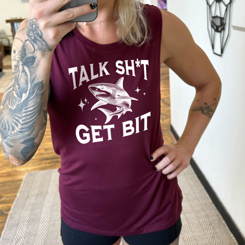 Model wearing maroon colored muscle tank with a shark graphic on it that says "Talk Shit Get Bit"