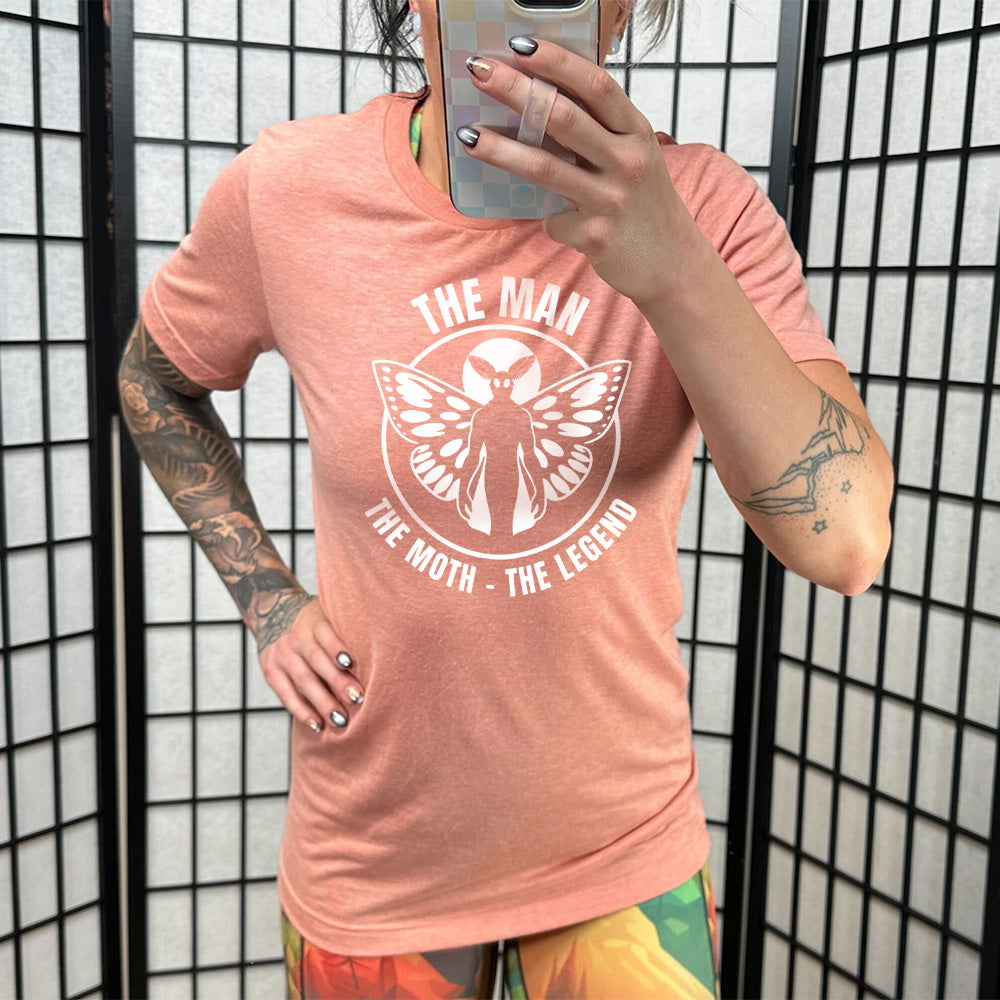 Model wearing sunset colored shirt with mothman graphic on it that says "The Man The Moth The Legend"