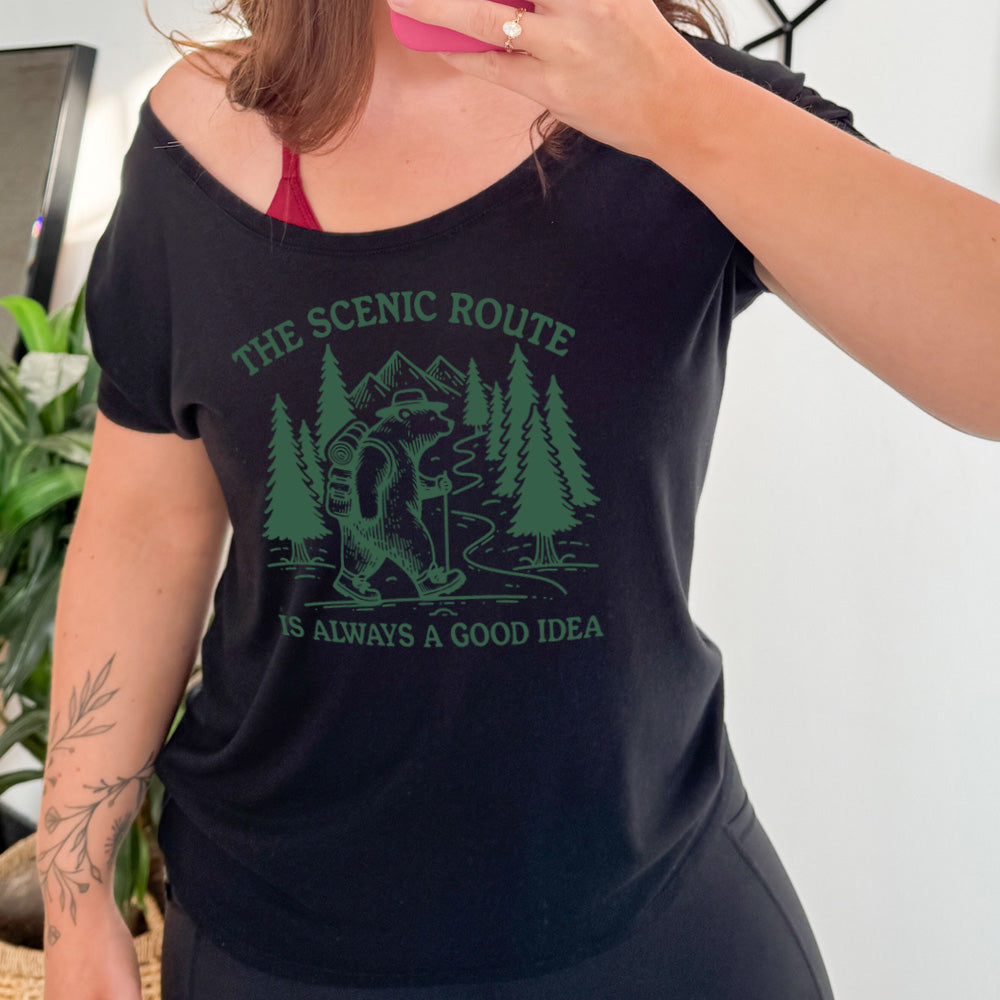 black slouchy tee with the words "the scenic route is always a good idea" with a bear hiking on a trail through the woods 