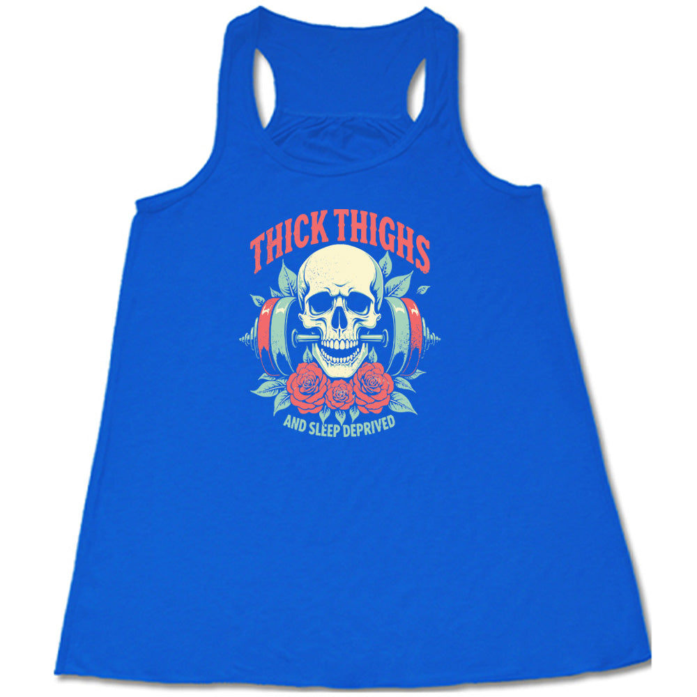 Blue colored flowy tank with a skull, flowers, and barbell graphic on it that says "Thick Thighs And Sleep Deprived" 
