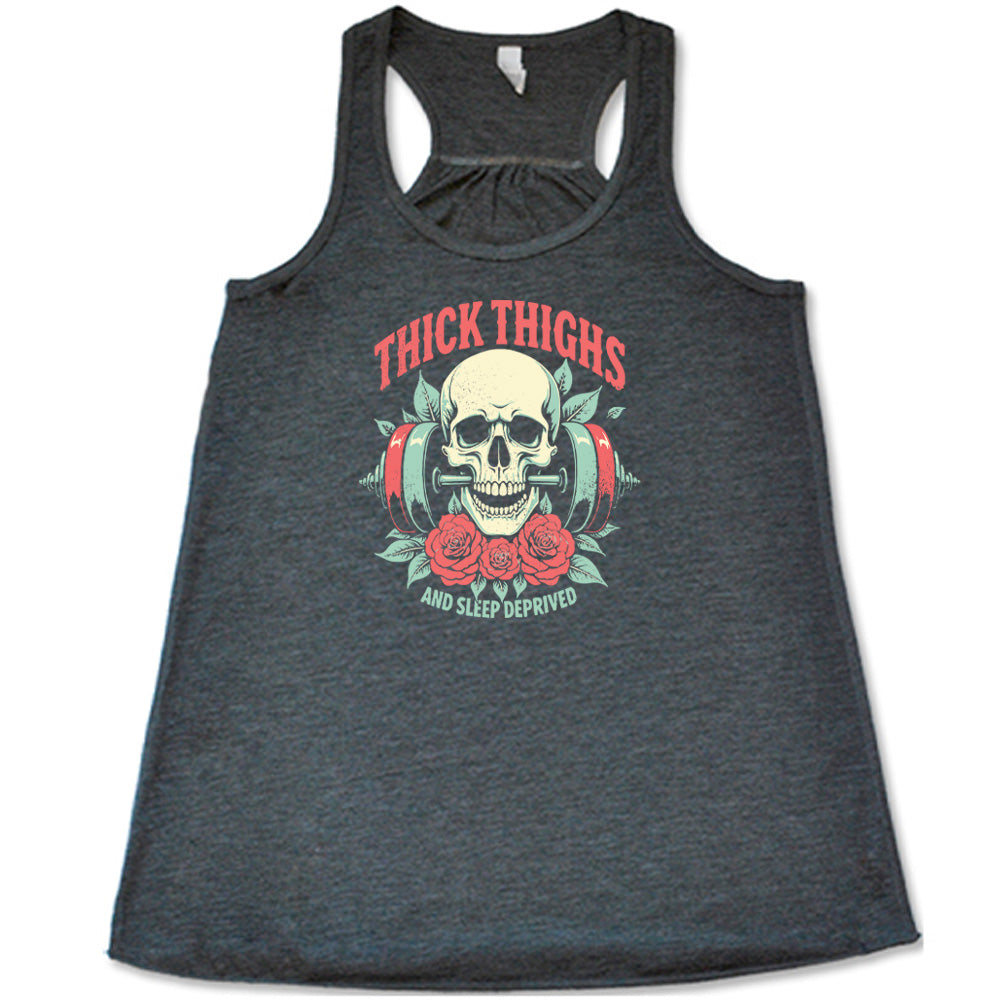 Grey colored flowy tank with a skull, flowers, and barbell graphic on it that says "Thick Thighs And Sleep Deprived" 