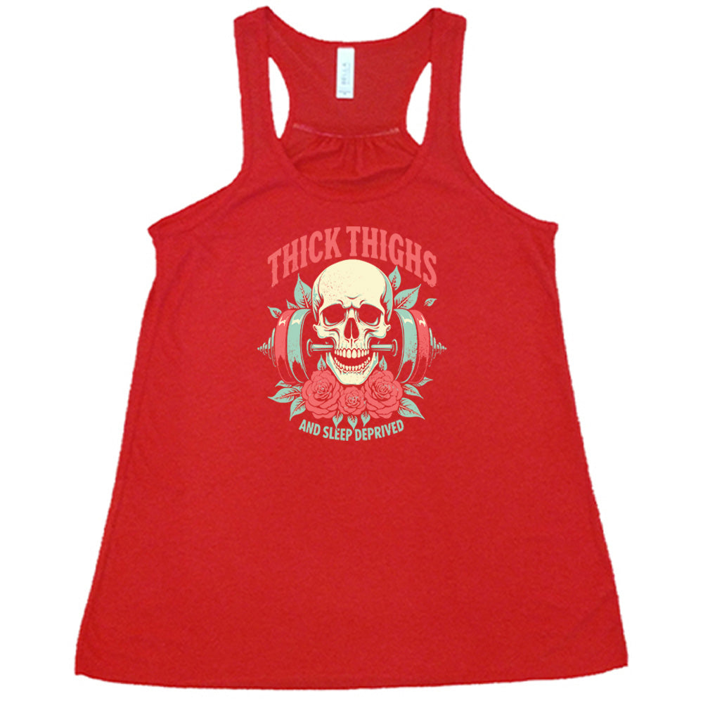 Red colored flowy tank with a skull, flowers, and barbell graphic on it that says "Thick Thighs And Sleep Deprived" 