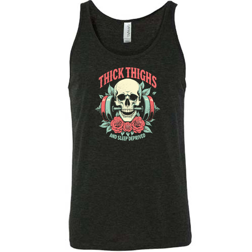 Black colored tank with a skull, flowers, and barbell graphic on it that says "Thick Thighs And Sleep Deprived" 