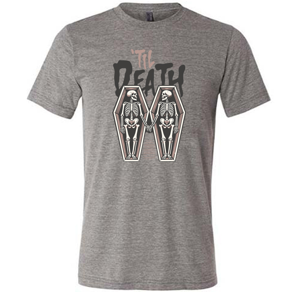grey unisex tee with the words "'til death" on it, with graphics of two skeletons, both in their own coffins, holding hands in the middle