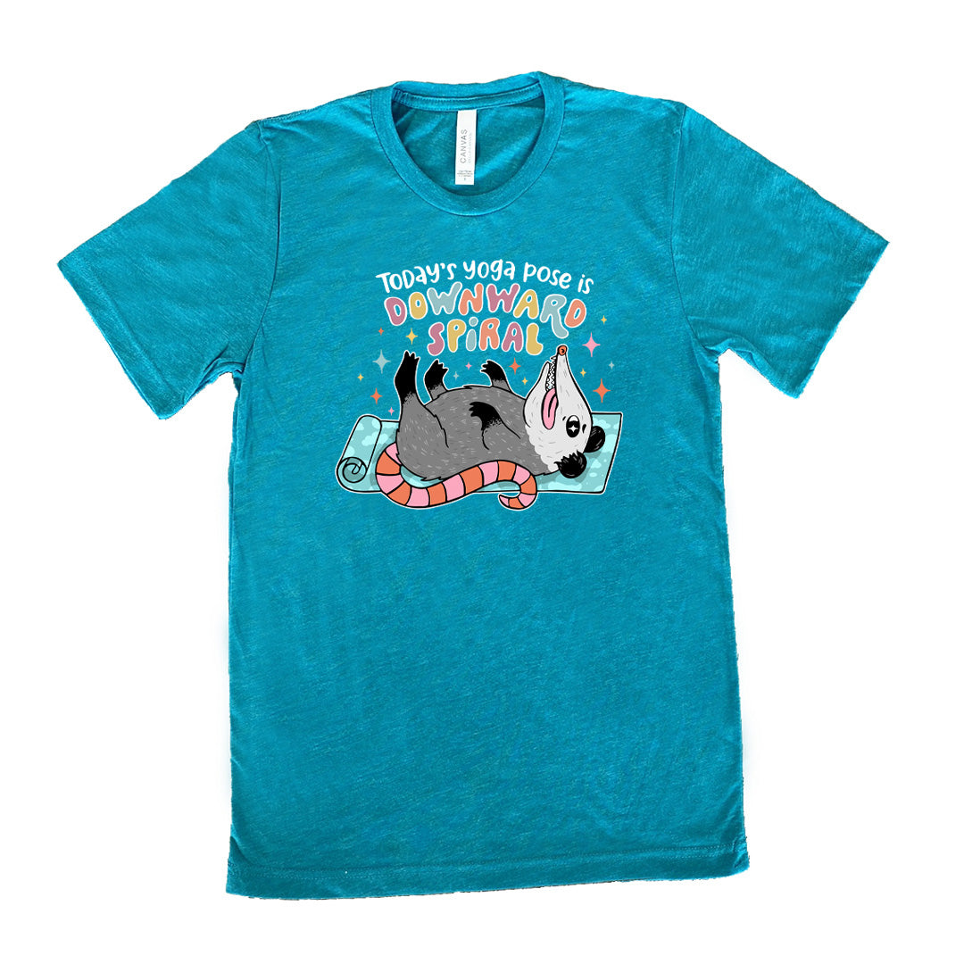 Teal unisex tee with the words "Today's yoga pose is a downward spiral" and the graphic of a possum playing dead on a yoga mat